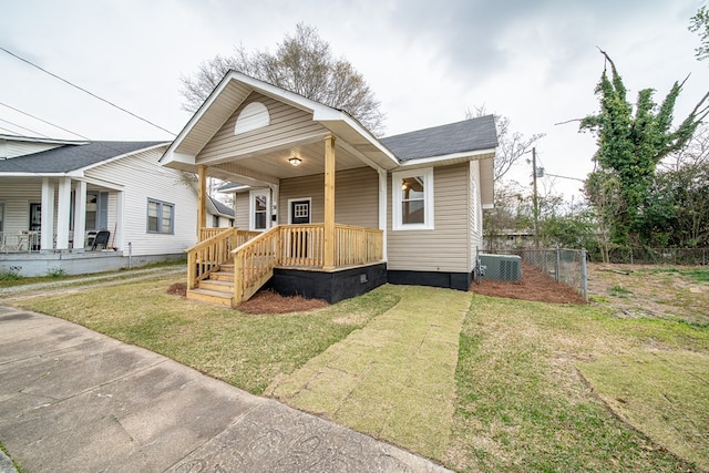 bungalow with a porch, cooling unit, fence, and a front yard