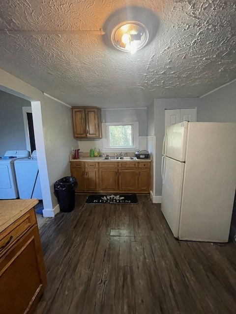 kitchen featuring sink, dark hardwood / wood-style floors, white refrigerator, a textured ceiling, and washer and dryer