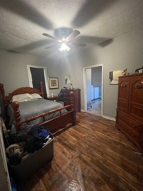 bedroom featuring washing machine and clothes dryer, ceiling fan, dark wood-type flooring, and a textured ceiling