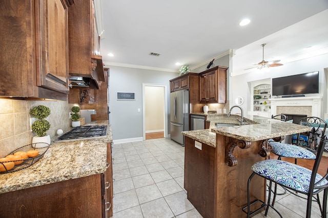 71 Greystone Ct, Smiths Station, AL 36877 - kitchen with stainless steel appliances, a sink, a breakfast bar area, ornamental molding, and a ceiling fan