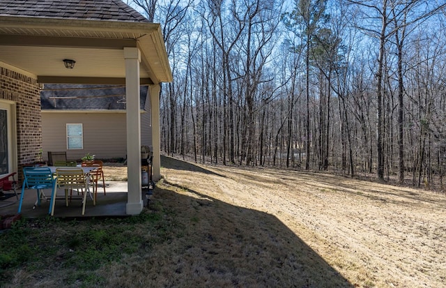 view of yard with a patio area and a view of trees