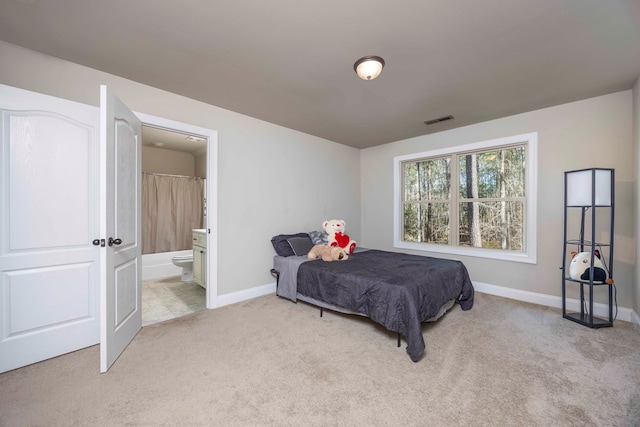 bedroom with visible vents, light colored carpet, connected bathroom, and baseboards