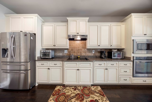 kitchen with dark stone counters, dark wood-style flooring, under cabinet range hood, and stainless steel appliances