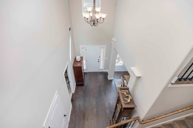 entryway with dark wood-type flooring, a notable chandelier, a high ceiling, and stairs