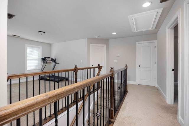 hall with visible vents, an upstairs landing, baseboards, light colored carpet, and attic access