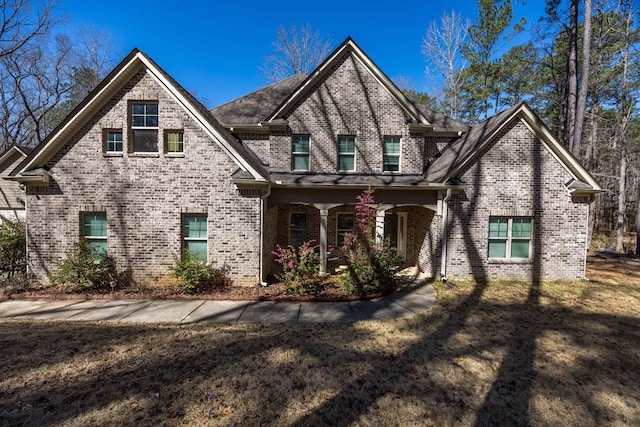 view of front facade featuring a porch, brick siding, and a front yard