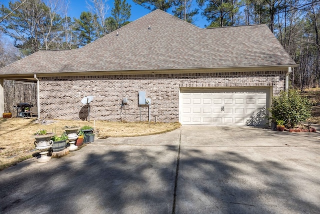 view of property exterior with concrete driveway, an attached garage, brick siding, and roof with shingles