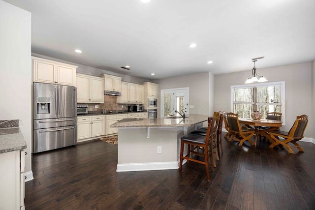 kitchen with dark wood-style floors, cream cabinetry, stainless steel appliances, and a sink