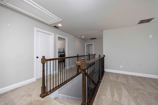 corridor with attic access, an upstairs landing, visible vents, and carpet floors