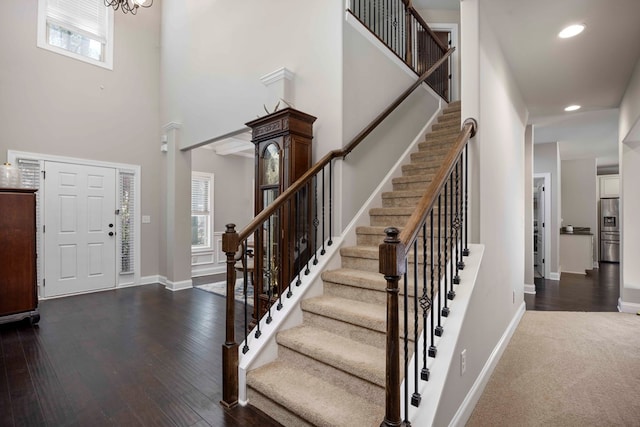 foyer featuring dark wood-style floors, baseboards, recessed lighting, stairs, and a towering ceiling