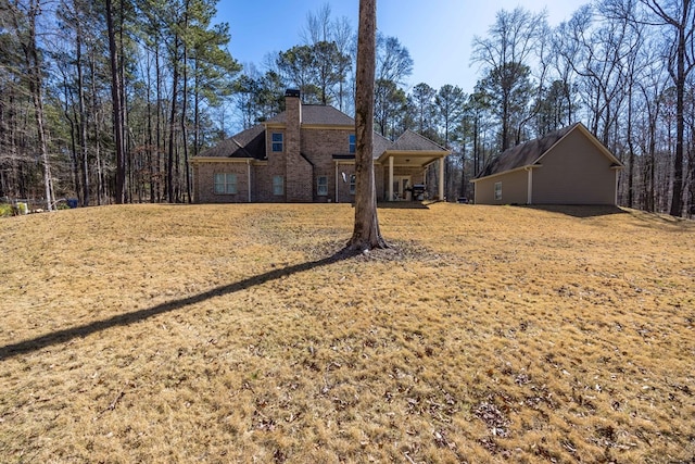 view of front of property featuring brick siding, a chimney, and a front yard