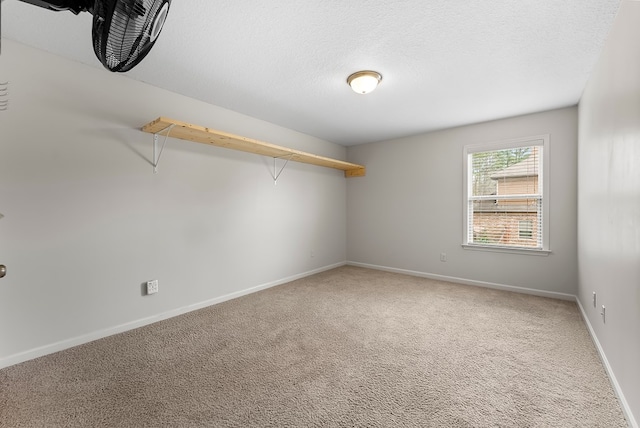 carpeted empty room featuring a textured ceiling and baseboards