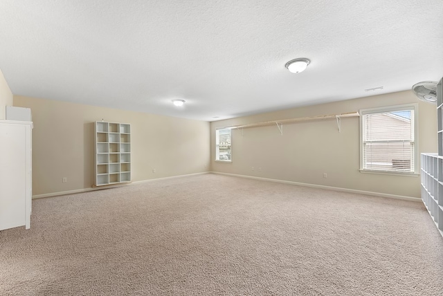 below grade area featuring a textured ceiling, carpet floors, and baseboards