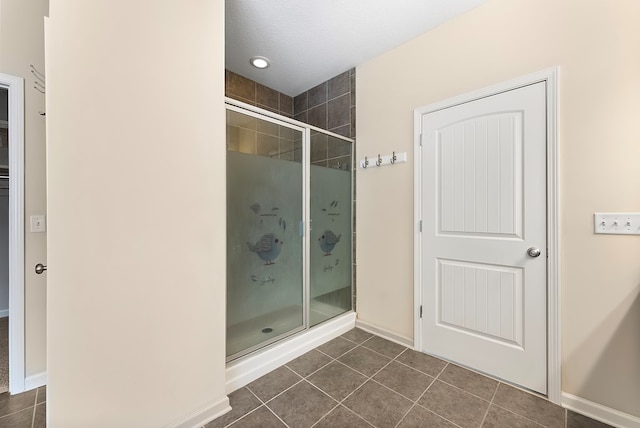 full bathroom with tile patterned flooring, a shower stall, a textured ceiling, and baseboards