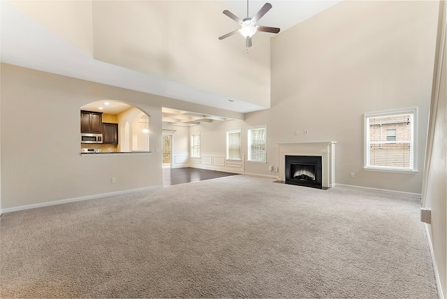 unfurnished living room featuring plenty of natural light, carpet floors, a ceiling fan, and a fireplace with flush hearth