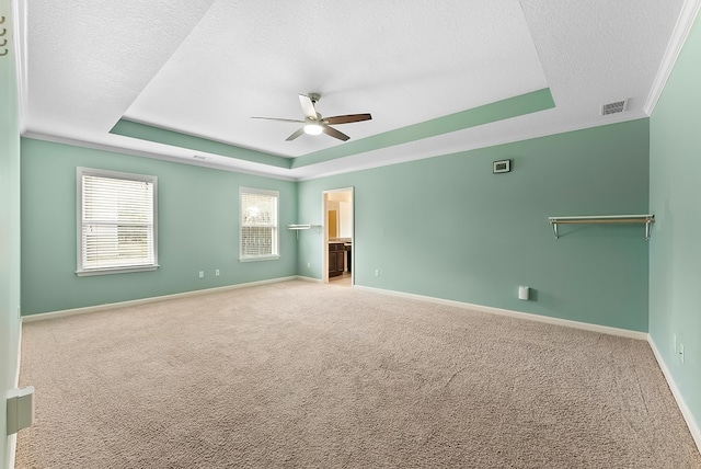 unfurnished room with a raised ceiling, light carpet, a textured ceiling, and visible vents