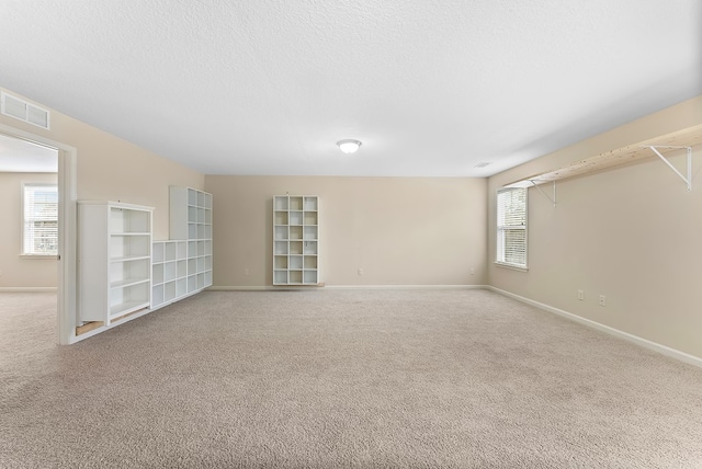 unfurnished room featuring plenty of natural light, light carpet, and visible vents