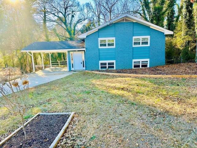 back of property with driveway, an attached carport, a lawn, and brick siding