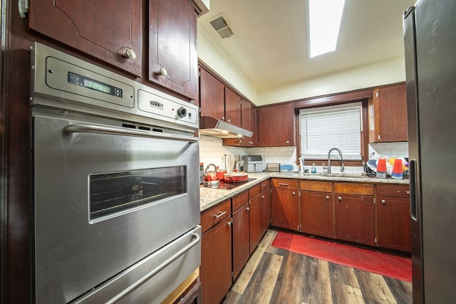 kitchen featuring appliances with stainless steel finishes, dark wood-style flooring, visible vents, and decorative backsplash