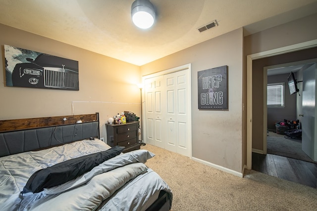 carpeted bedroom featuring baseboards, visible vents, and a closet