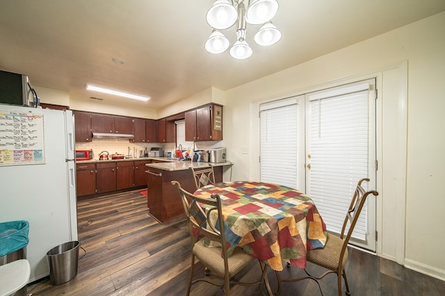 interior space with a peninsula, white appliances, under cabinet range hood, and dark wood finished floors