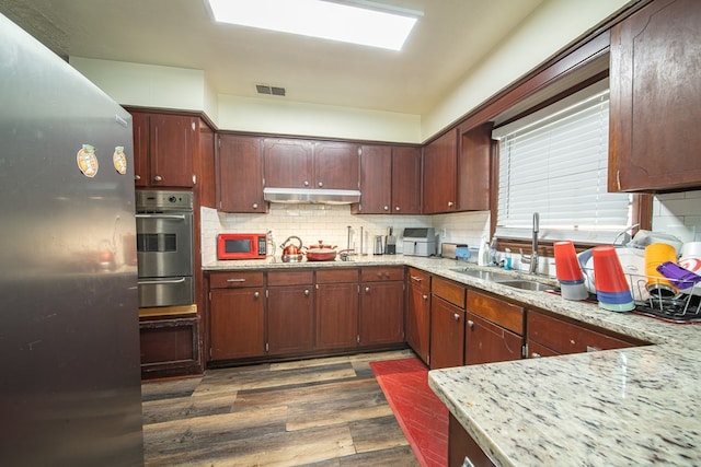 kitchen with visible vents, decorative backsplash, dark wood-type flooring, a sink, and oven