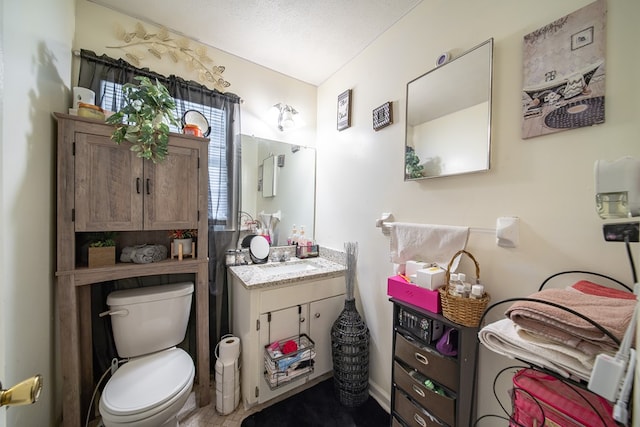 bathroom with a textured ceiling, vanity, and toilet