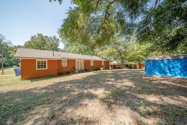 rear view of property featuring french doors, brick siding, and a yard