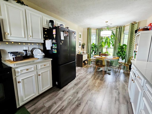 7 Hillside Ct, Phenix City, AL 36870 - kitchen with black appliances, light wood finished floors, white cabinetry, tasteful backsplash, and a textured ceiling