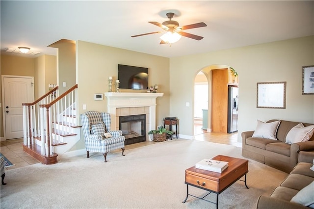 93 Pebble Ct, Smiths Station, AL 36877 - living area featuring arched walkways, ceiling fan, stairway, light colored carpet, and a tiled fireplace