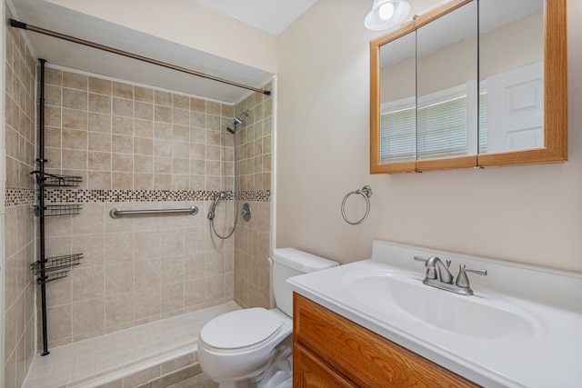 full bathroom with toilet, a tile shower, and vanity