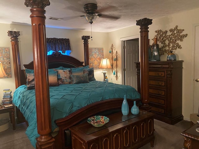 carpeted bedroom featuring a textured ceiling, visible vents, a ceiling fan, and ornate columns