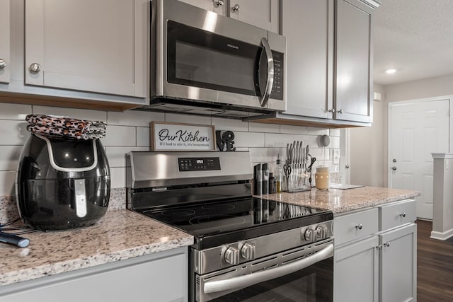 6368 Sandy Bottom Dr, Columbus, GA 31907 - kitchen with stainless steel appliances, tasteful backsplash, dark wood-type flooring, light stone countertops, and a textured ceiling
