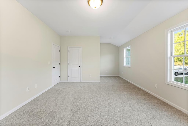 carpeted spare room featuring a healthy amount of sunlight and vaulted ceiling