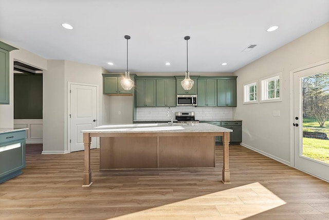 kitchen featuring green cabinets, appliances with stainless steel finishes, and light hardwood / wood-style flooring