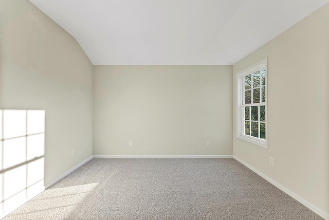 spare room with light carpet and vaulted ceiling