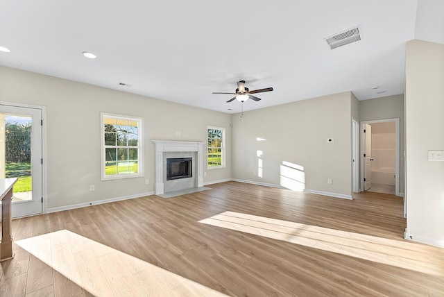 unfurnished living room featuring ceiling fan, light wood-type flooring, and a high end fireplace