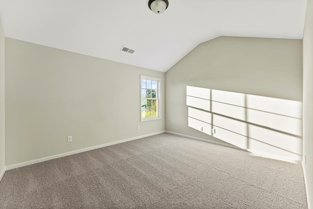 carpeted empty room with vaulted ceiling