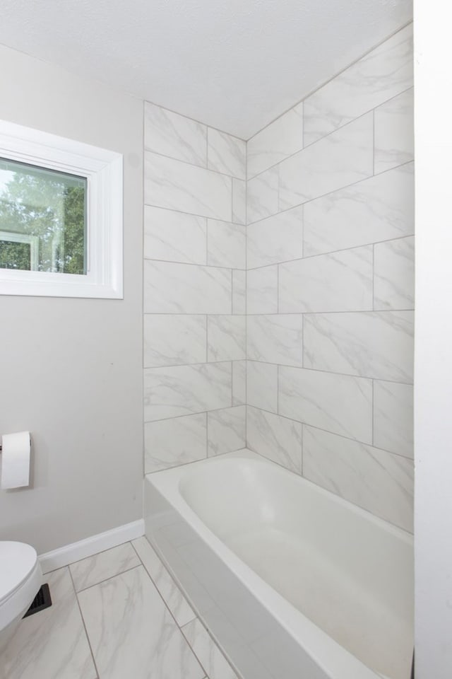 bathroom with tiled shower / bath combo and toilet