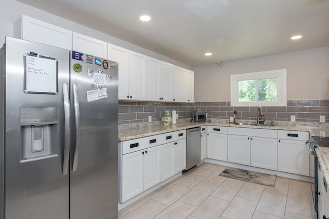 kitchen with light stone countertops, sink, white cabinetry, and stainless steel appliances