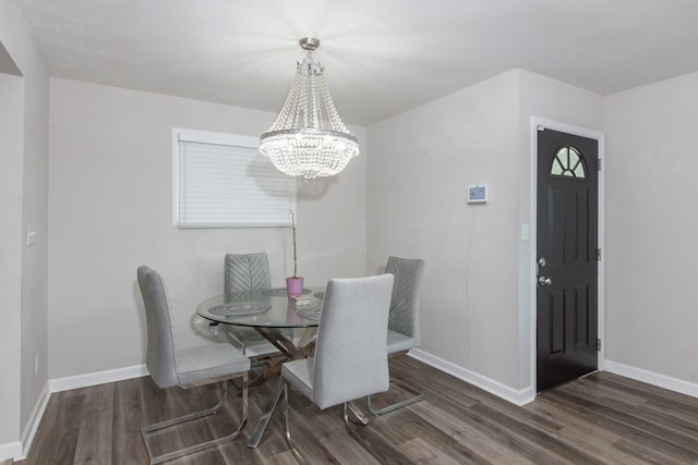 dining space with dark hardwood / wood-style flooring and an inviting chandelier