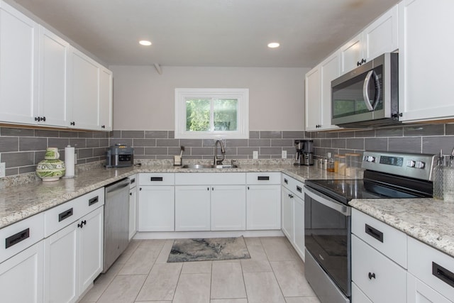 kitchen with white cabinets, sink, light stone countertops, light tile patterned flooring, and stainless steel appliances