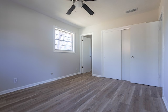 unfurnished bedroom featuring visible vents, a closet, a ceiling fan, and wood finished floors