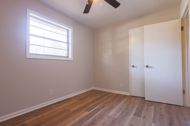 empty room with baseboards, a ceiling fan, and wood finished floors
