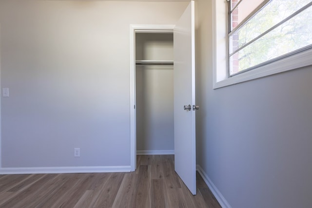 unfurnished bedroom with a closet, baseboards, and wood finished floors