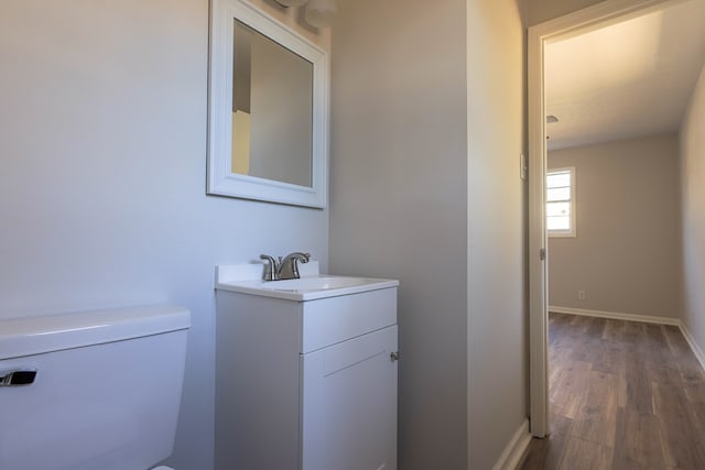 bathroom with vanity, baseboards, toilet, and wood finished floors