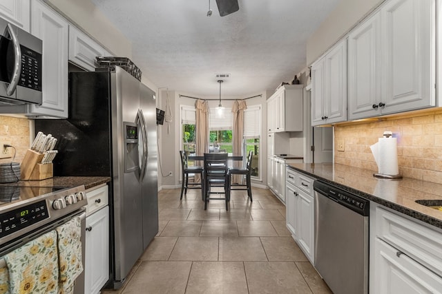 5936 Manassas Dr, Columbus, GA 31909 - kitchen featuring stainless steel appliances, white cabinets, decorative backsplash, light tile patterned floors, and hanging light fixtures