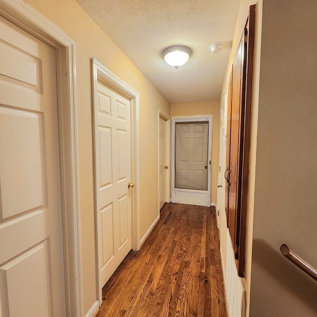 hall featuring a textured ceiling and dark hardwood / wood-style floors