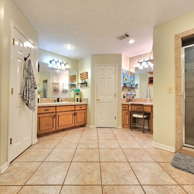 bathroom featuring tile patterned flooring, vanity, an enclosed shower, and a textured ceiling