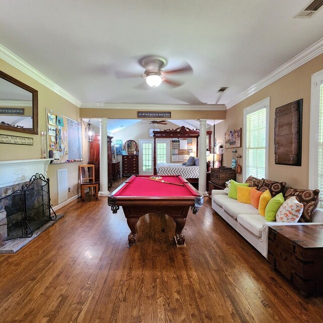 recreation room featuring hardwood / wood-style flooring, ornate columns, crown molding, and a wealth of natural light